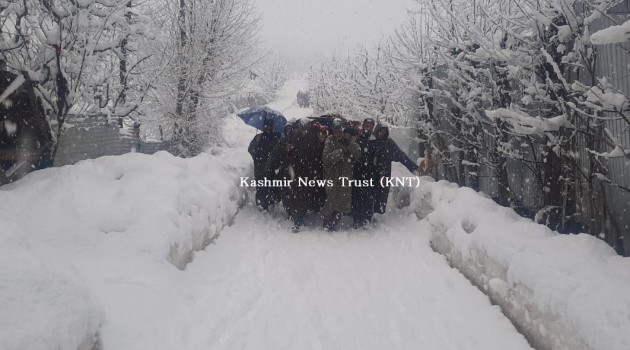 Amid snowfall, local Muslims walk on foot to shoulder the dead body of a Pandit stuck in an ambulance in South Kashmir